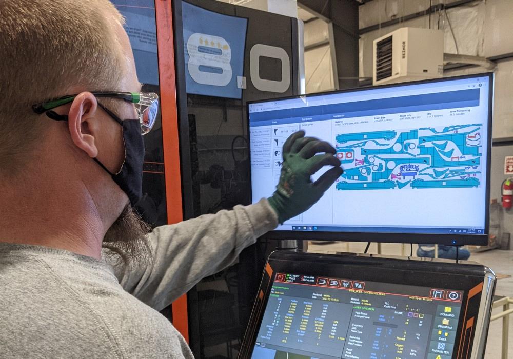 An operator adjusts a nest of parts, delivered to the machine via OSH Cut’s custom software