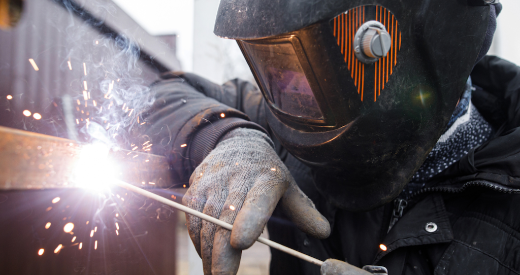 Shielded metal arc welding. Worker welding metal with electrodes.